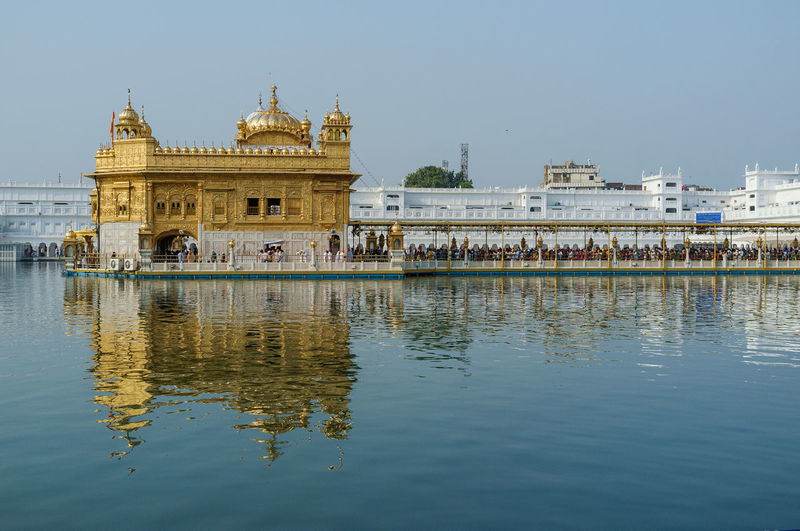 Golden temple over lake against clear sky