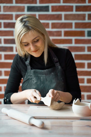 Woman making bowl with clay on table