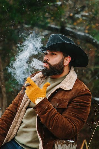Man smoking cigar while standing outdoors