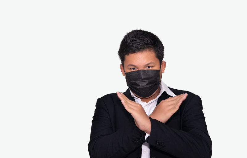 Portrait of young man standing against white background