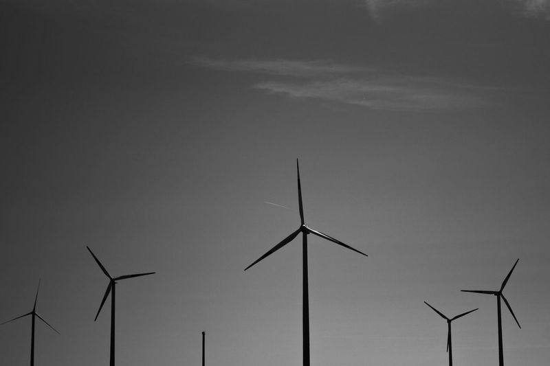 Low angle view of windmills against sky