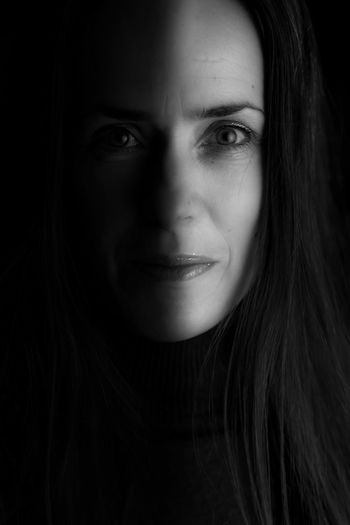 Close-up portrait of beautiful woman against black background