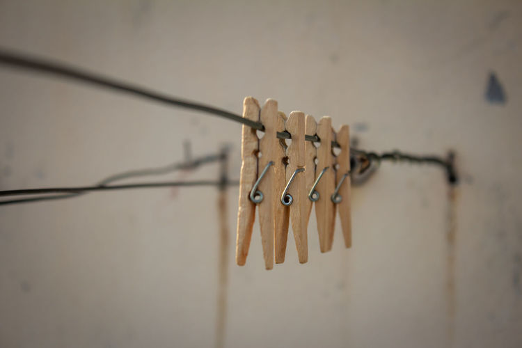 Close-up of clothespins hanging on clothesline against wall