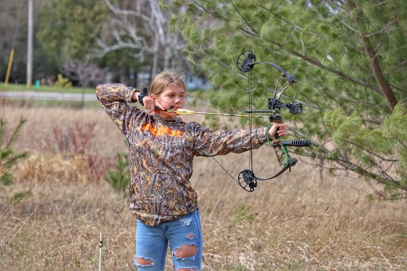 Full length of young lady shooting a bow