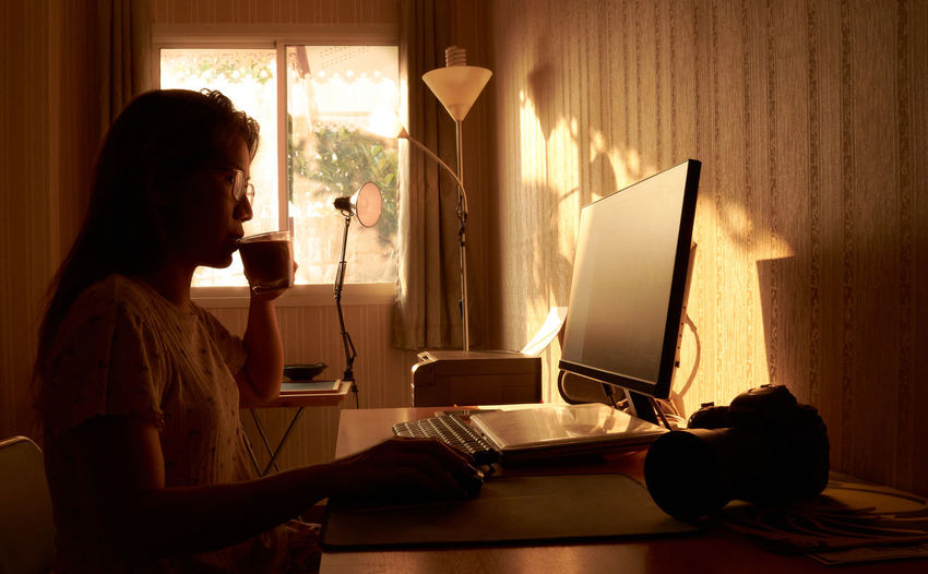 Side view of woman using mobile phone at home