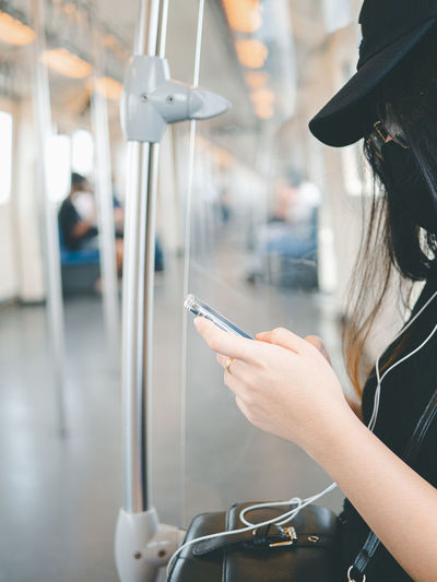 Close-up woman wear protective mask and using smartphone in public transport.