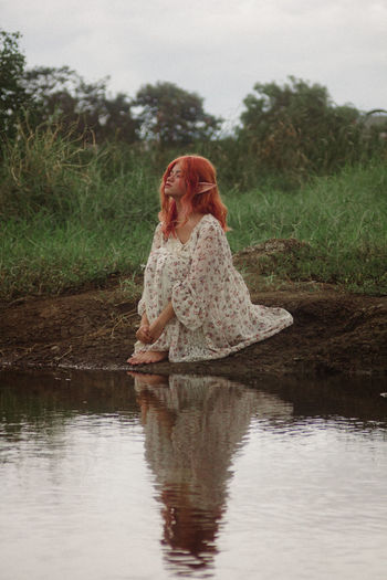 Young woman sitting by lake