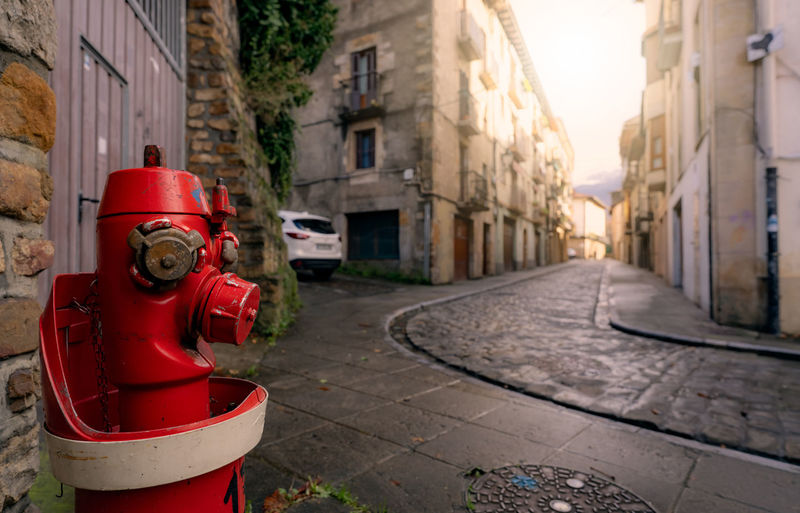 Red fire hydrant on sidewalk in onati city, spain. fire hydrant on blur old building, white car