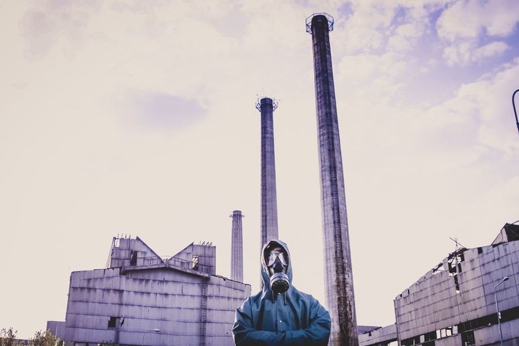 Low angle view of man wearing gas mask standing against factory