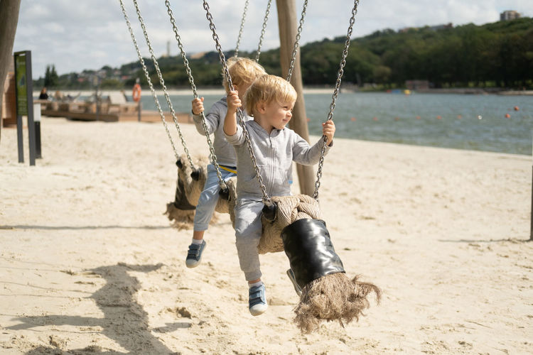 Cute kids playing on swing at beach