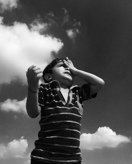 Low angle view of boy crying against sky