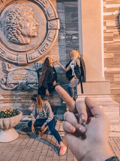 Cropped hand showing middle finger against female friends