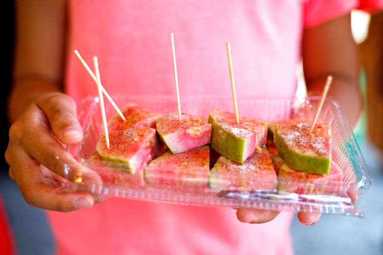 Midsection of woman holding guava slices in container