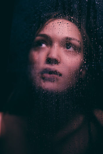 Close-up portrait of a young woman in rain