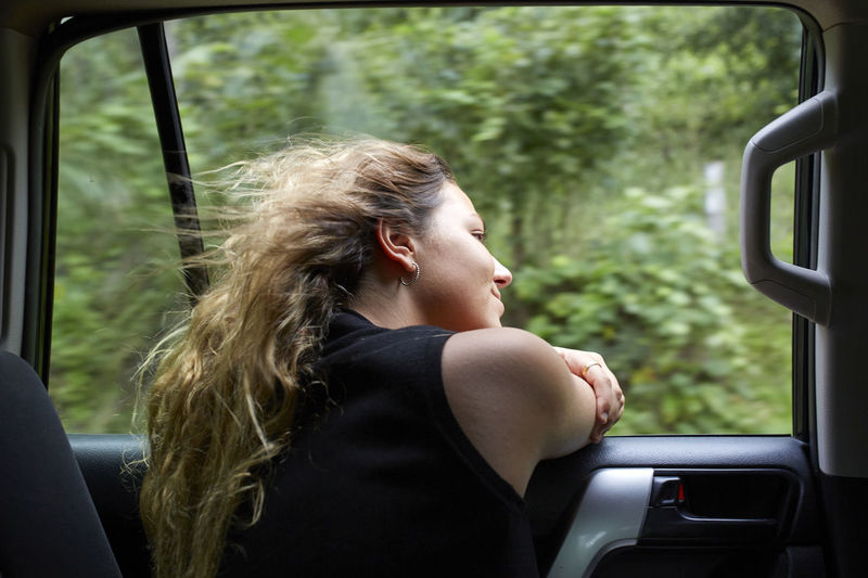 Side view of young woman sitting in car