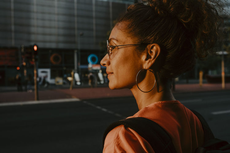 Businesswoman looking away in city during sunset