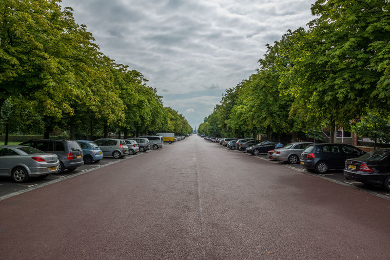 Cars parked on road against cloudy sky