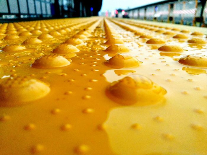 Surface level of wet yellow tactile paving at railroad station platform