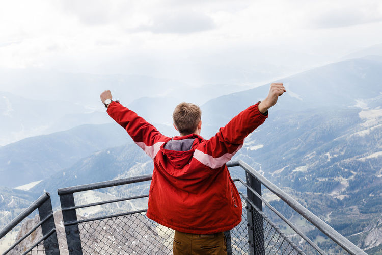 Millennial guy enjoys mountain views of alps from observation deck