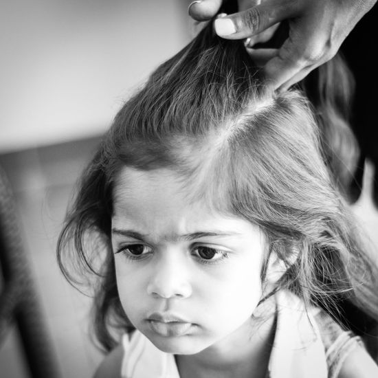 Close-up of adult doing girl's hair