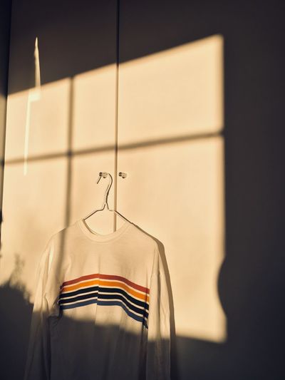 Close-up of rainbow sweater hanging on wall at home