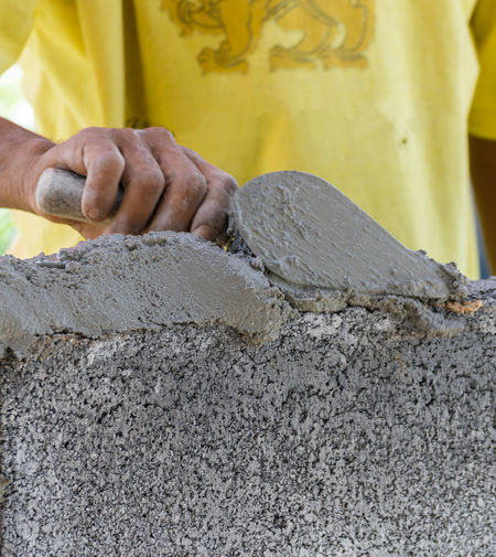 Midsection of bricklayer working with cement at construction site