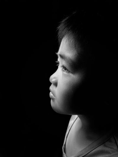 Close-up of boy looking away in darkroom