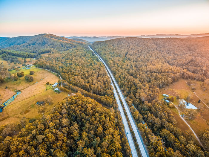 Highway passing through scenic countryside at sunset - aerial view