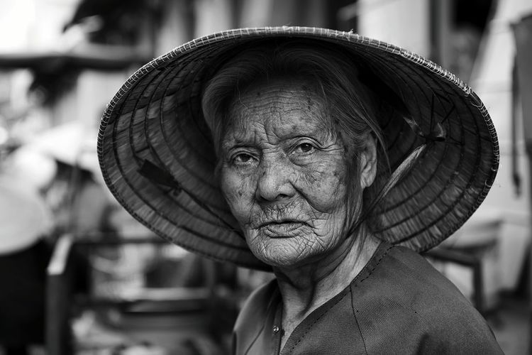 Close-up portrait of senior woman wearing asian style conical hat outdoors