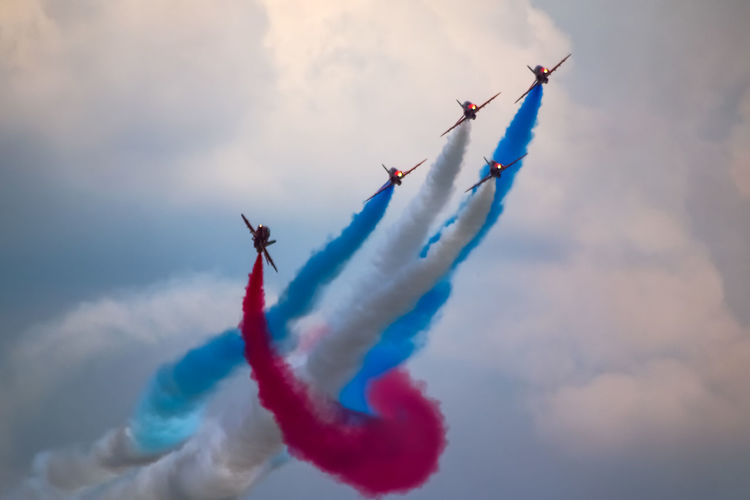 Low angle view of airshow against cloudy sky