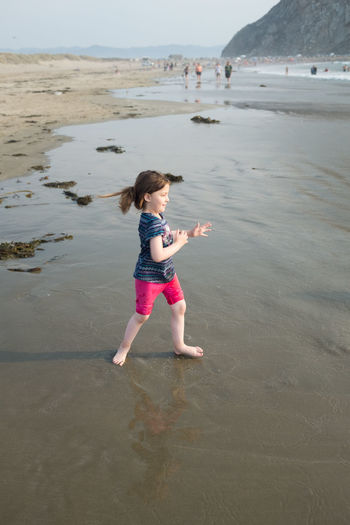 Full length of girl enjoying on shore at on beach