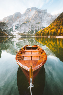 Wooden boat moored in lake by mountains