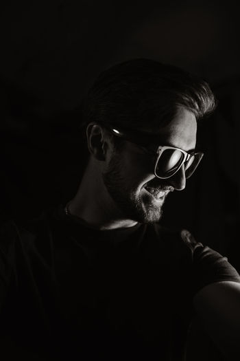 Portrait of young man wearing eyeglasses against black background