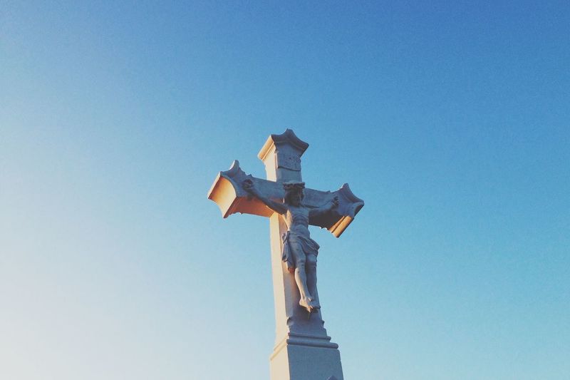 Low angle view of jesus christ on cross against clear sky