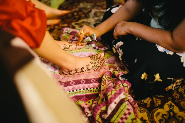 Close-up of woman tattooing leg of bride with henna