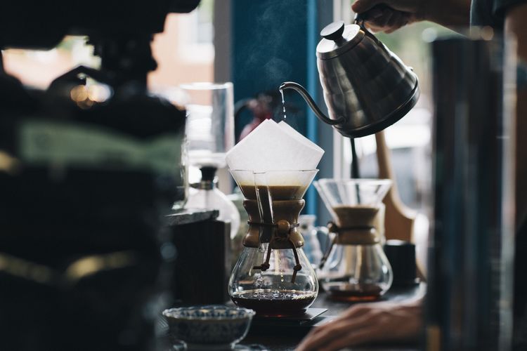 Close-up of hand pouring coffee in cafe