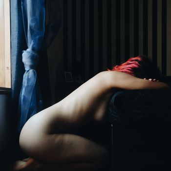 Side view of naked woman kneeling at home