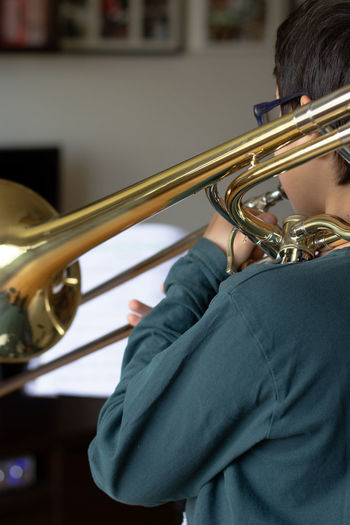 Rear view of boy playing trumpet at home