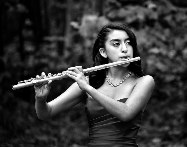 Portrait of beautiful young woman playing the flute 