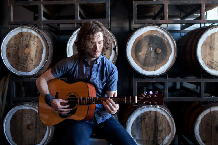 Young man playing acoustic guitar in a distillery