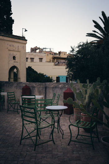 Empty chairs and tables against buildings in city
