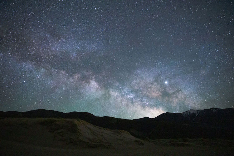 Scenic view of silhouette mountains against sky at night