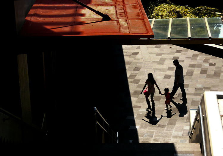 High angle view of family walking outside building during sunny day