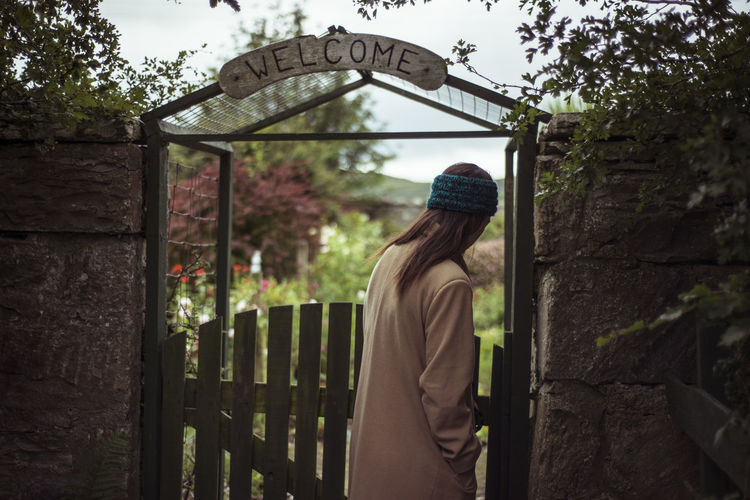 Person enters lush garden gate with welcome sign