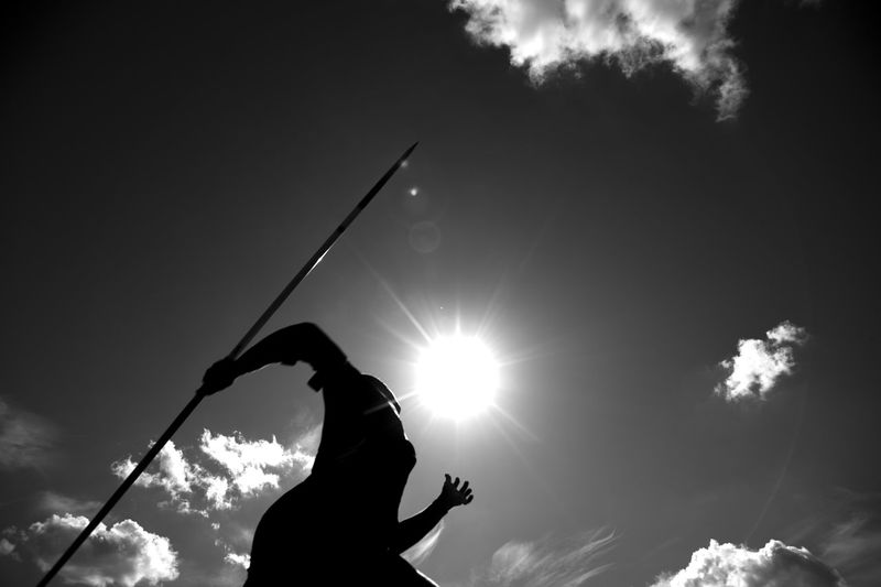 Low angle view of silhouette woman holding sun against sky