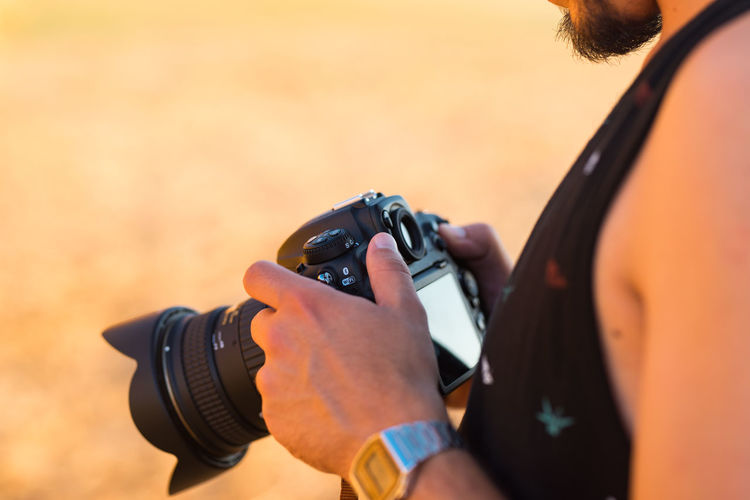 Midsection of man holding digital camera