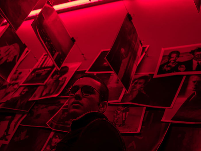Man standing against photographs in red room