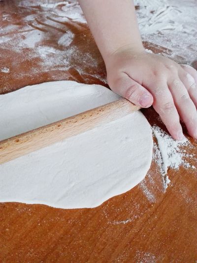 Cropped hand rolling dough on table