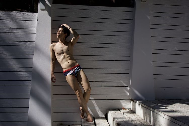 A man lean against wall in swimming suit