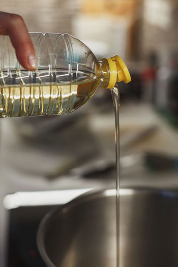Close up of pouring vegetable oil into deep cooking stainless steel pot